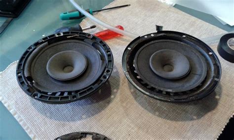 Imagen detallada de la limpieza de un altavoz de smartphone con un cepillo pequeño y aire comprimido.