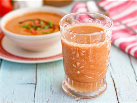 Plato de gazpacho fresco con guarniciones saludables y un vaso de agua.