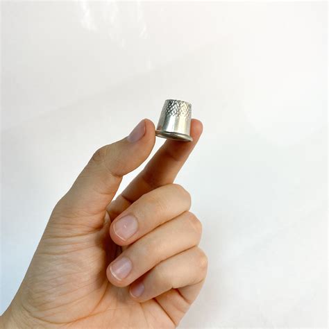 Persona tocando un objeto metálico con un dedal en el dedo para descargar electricidad estática.