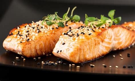 Plato de salmón a la plancha con semillas de sésamo y guarnición de verduras.