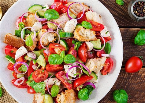 Plato servido de ensalada Panzanella con trozos de pollo a la parrilla y verduras frescas.