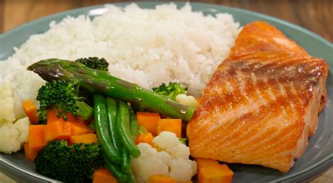 Imagen de un bol de arroz integral con salmón, aguacate y verduras, representando una comida equilibrada.