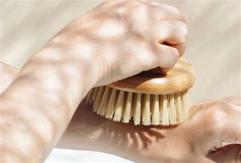 Fotografía de un cepillo para cuerpo seco y demostración de la técnica de cepillado en seco, enfocándose en movimientos ascendentes hacia el corazón.