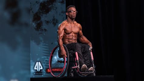 Atleta de culturismo en silla de ruedas realizando una pose de doble bíceps.