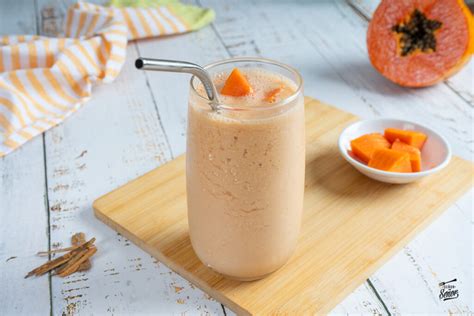 Imagen de un batido cremoso de papaya y avena en un vaso, con trozos de fruta fresca alrededor.