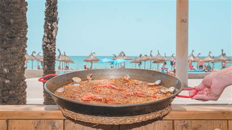 Imagen de una paella servida en un chiringuito junto al mar en la Malvarrosa