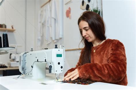 Foto de una modista trabajando en una máquina de coser, rodeada de telas y patrones.
