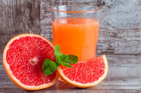 Ilustración de un vaso de jugo de toronja y jengibre rodeado de frutas y raíces beneficiosas