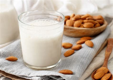 Imagen de un puñado de almendras junto a un vaso de leche de almendras