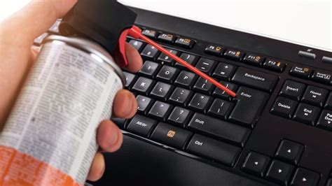 Imagen de un teclado Asus siendo limpiado con un cepillo suave y aire comprimido.