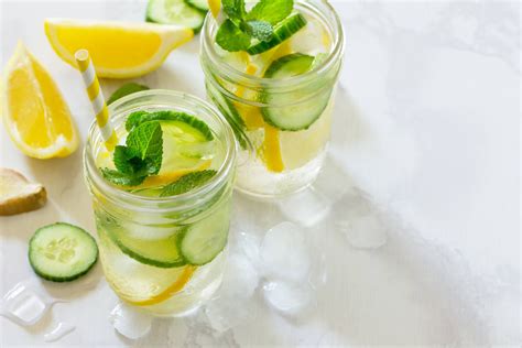 Imagen de rodajas de limón, pepino y jengibre flotando en agua con hojas de menta
