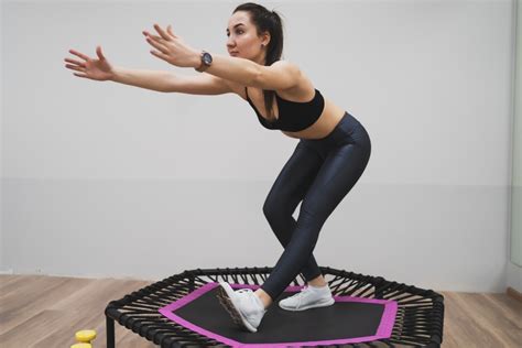 Mujer realizando ejercicios de rebote en un mini trampolín con una expresión de energía.