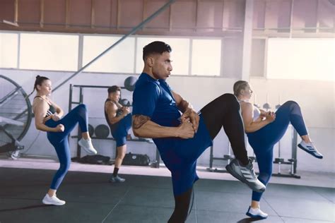 Instructor liderando una clase de BodyCombat con participantes realizando movimientos de artes marciales al ritmo de la música.