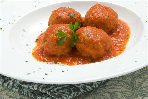 Plato humeante de albóndigas paleo en salsa de tomate, servido en una olla de cocción lenta.