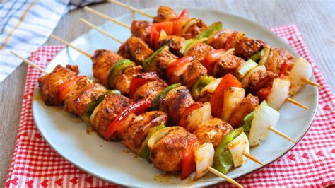 Brochetas coloridas de verduras y trozos de pollo a la parrilla.