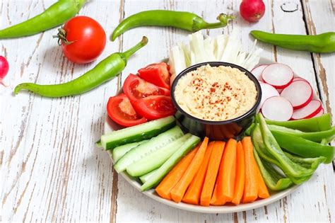 Foto de un plato de hummus casero con palitos de verduras.