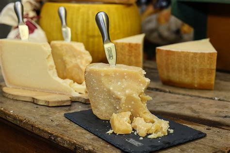 Un primer plano de un bloque de queso Parmigiano Reggiano con un rallador al lado.