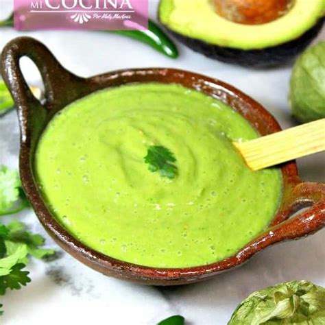 Un primer plano de una salsa de aguacate cremosa en un bol, decorada con un poco de cilantro picado.