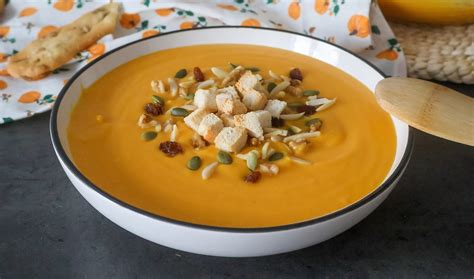 Imagen de un bol humeante de crema de calabaza decorada con semillas.