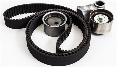 Imagen de una correa de distribución desgastada y una nueva junto a tensores y una bomba de agua.