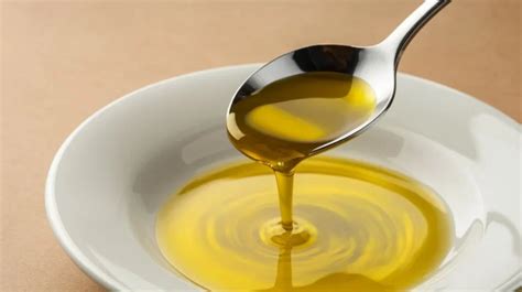 Ilustración de una cucharada de aceite de oliva virgen extra junto a medio limón.