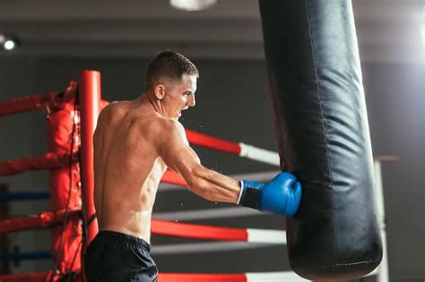 Boxeador golpeando un saco de boxeo, mostrando la tensión muscular en brazos y torso.