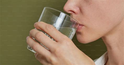 Persona bebiendo un vaso de agua antes de una comida.