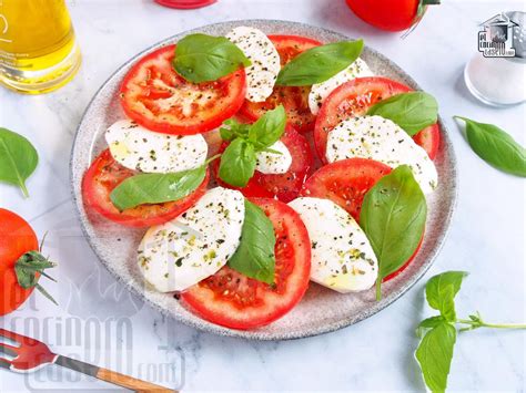 Ingredientes frescos para la ensalada Caprese con melocotón, destacando el tomate, la mozzarella y los melocotones cortados.