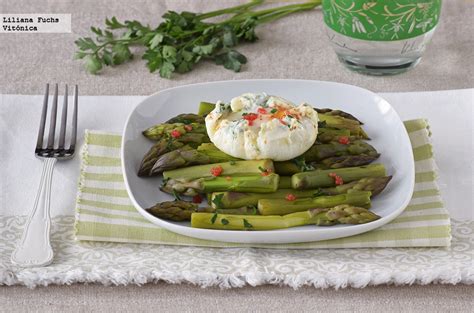 Espárragos al vapor servidos con un huevo poché en la parte superior, listos para ser consumidos.